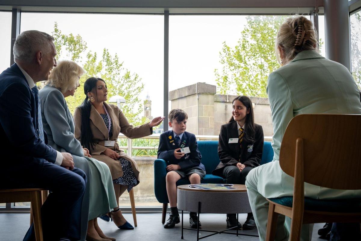 Her Majesty The Queen sits down with children from Bradford with Sharena and school children