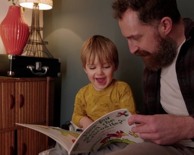 Father and toddler son read a picture book together. Early Words Matter