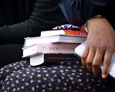 Pile of books on a woman's lap