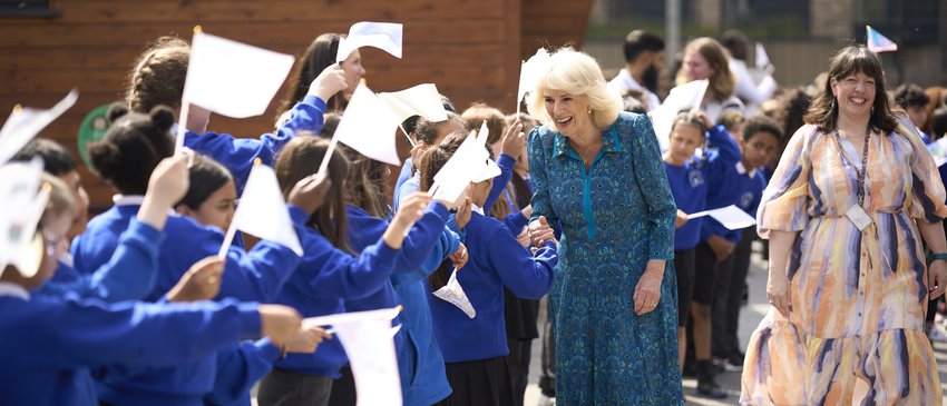 Her Majesty Queen Camilla greeting Moreland Primary School pupils who are waving flags decorated with their favourite book characters. (Credit: WeShootLondon)