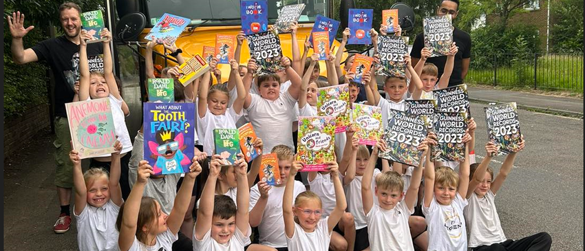 Young pupils holding up books above their heads