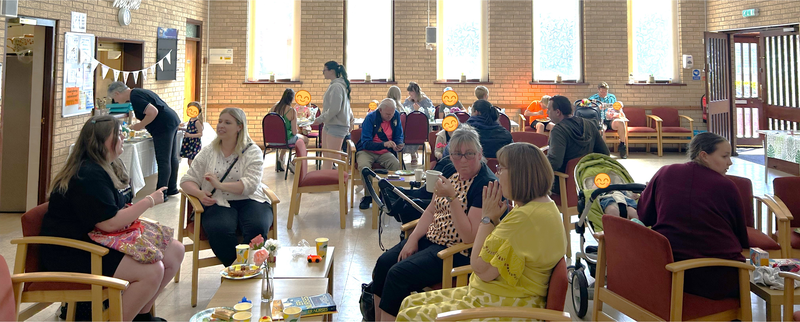 An image of people networking in a church hall and enjoying drinks and food