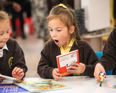 Two primary school children look at books excitedly as part of the Young Readers Programme