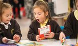 Two primary school children look at books excitedly as part of the Young Readers Programme