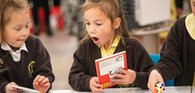 Two primary school children look at books excitedly as part of the Young Readers Programme