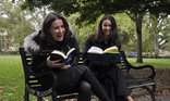 Two women enjoying reading on a park bench