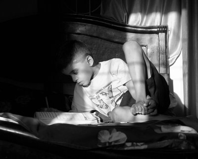 Boy reads a book on his bed - greyscale - reading for pleasure