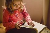 Little girl reads a book on her own