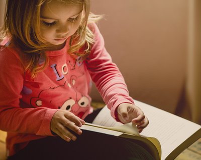 Little girl reads a book on her own