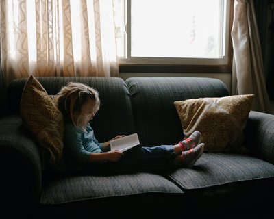 Child reads on a sofa - Unsplash image