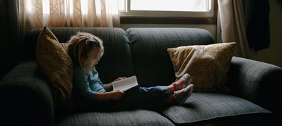 Child reads on a sofa - Unsplash image