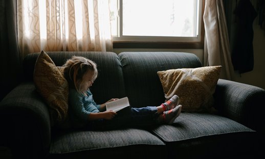 Child reads on a sofa - Unsplash image